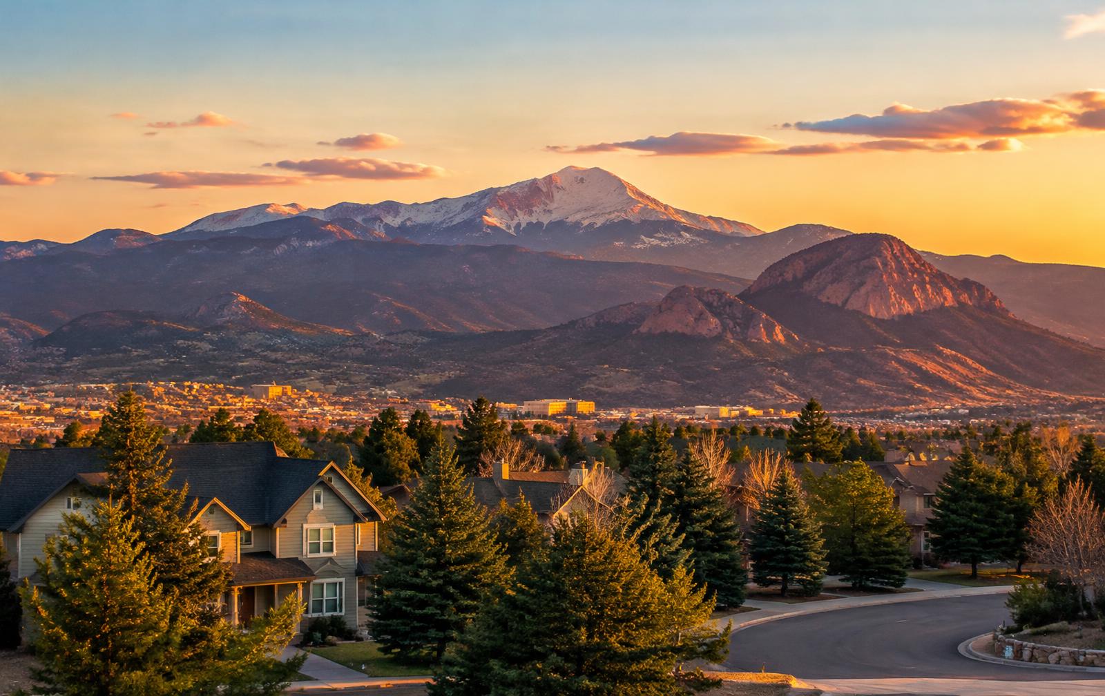 Colorado Springs homes beneath Pikes Peak and Cheyenne Mountain at sunset